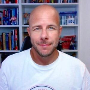 Daniel Peris sits in front of bookshelves, shown in a cropped portrait.